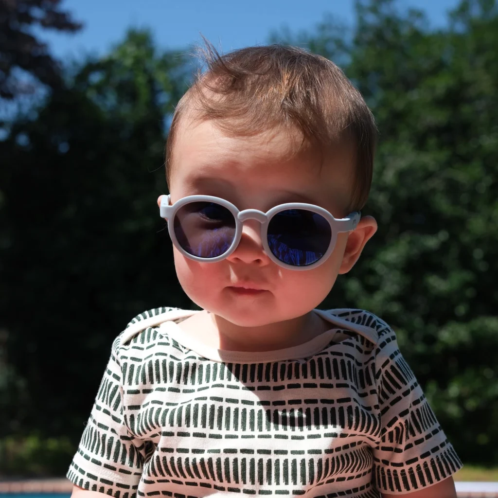 A 2-year-old boy wearing KiGO sunglasses in the sunlight.