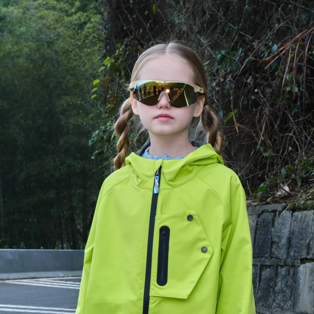 A 6-year-old girl is wearing KiGO sports sunglasses suitable for ages 3-6 on the road.