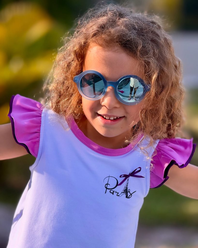 Why kids need polarized sunglasses? A girl wearing KiGO kids polarized sunglasses Standing in the sun.