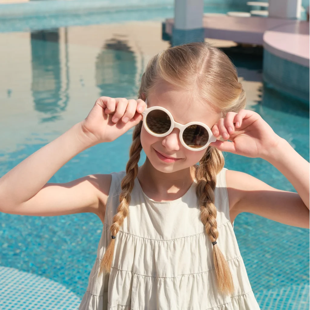 A 5-year-old girl wearing KiGO bendy kid sunglasses stands by the pool.