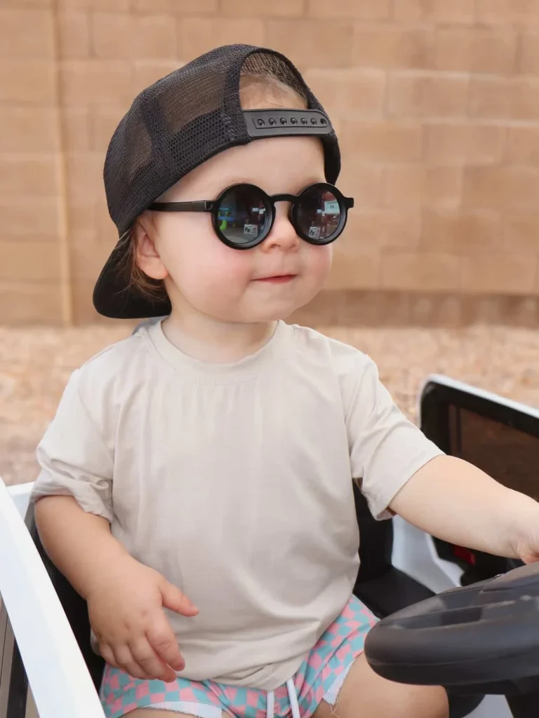 A 1.5 year old boy drives a toy car wearing KiGO California 0-24 months best quality kids sunglasses.