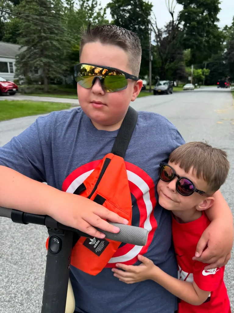 A pair of brothers wearing KiGO California best kids polarized sunglasses for 6-12 years while playing outdoors.